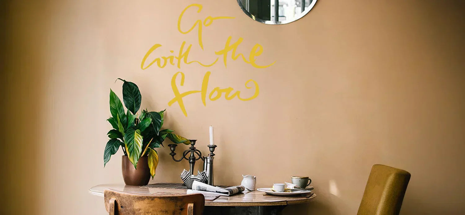 Wandtattoo „Go with the flow“ in Gold Matt – stilvolles, gelbes Wandmotiv, das Leichtigkeit und Lebensfreude vermittelt.