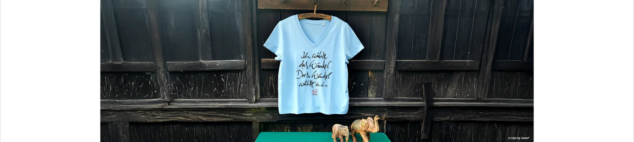 Blaues T-Shirt an einer Holzwand aus dem Onlineshop SignShop Tirol