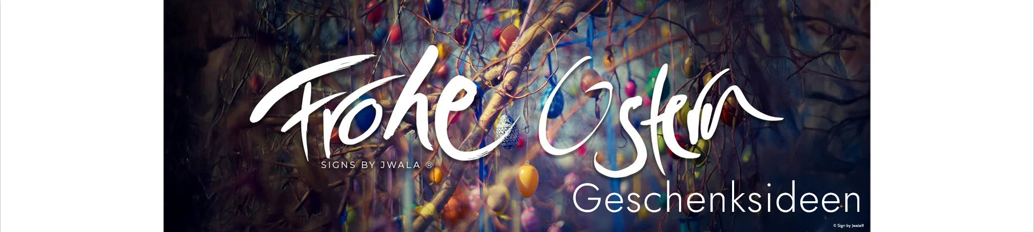 Ostereier an Ästen und der weiße Schriftzug „Frohe Ostern“ im Jwala® Stil im Vordergrund aus dem Onlineshop SignShop Tirol.