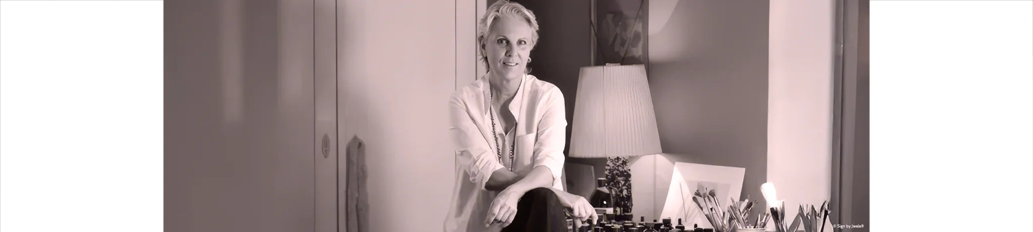 Jwala Gamper mit warmem Lächeln, freundlich und offen im sanften Licht vor dezentem Hintergrund.