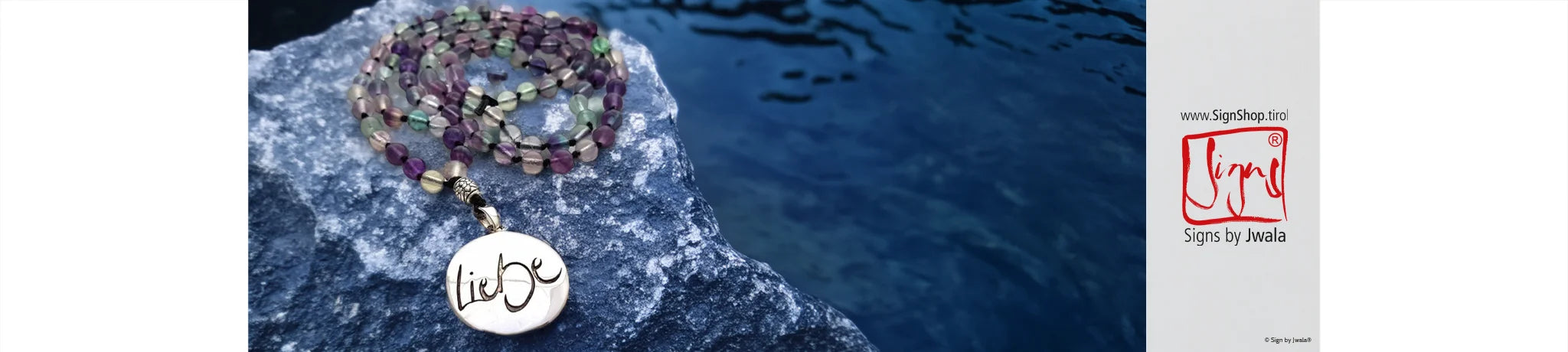 Das Bild zeigt eine handgefertigte Mala-Ketten in sanften Grün- und Türkistönen, liebevoll auf hellem Untergrund arrangiert, umgeben von Naturmaterialien.