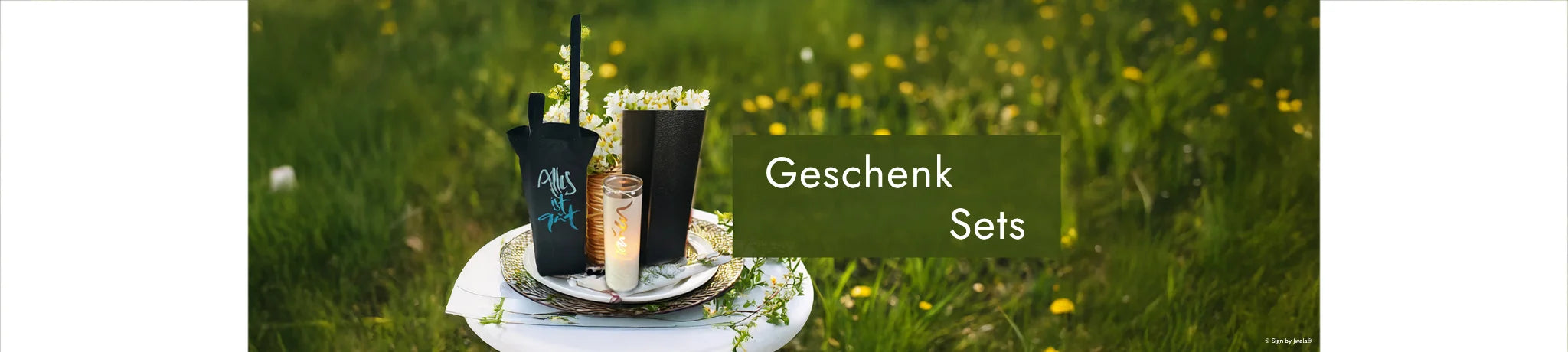 Kerze mit Botschaft und Flaschentasche mit Sprüche aus dem Onlineshop SignShop Tirol, liebevoll in einer Wiese dekoriert.